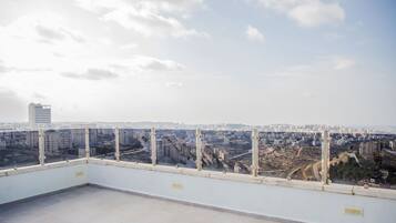 A rooftop terrace with a cityscape view, including several high-rise buildings and a clear sky.