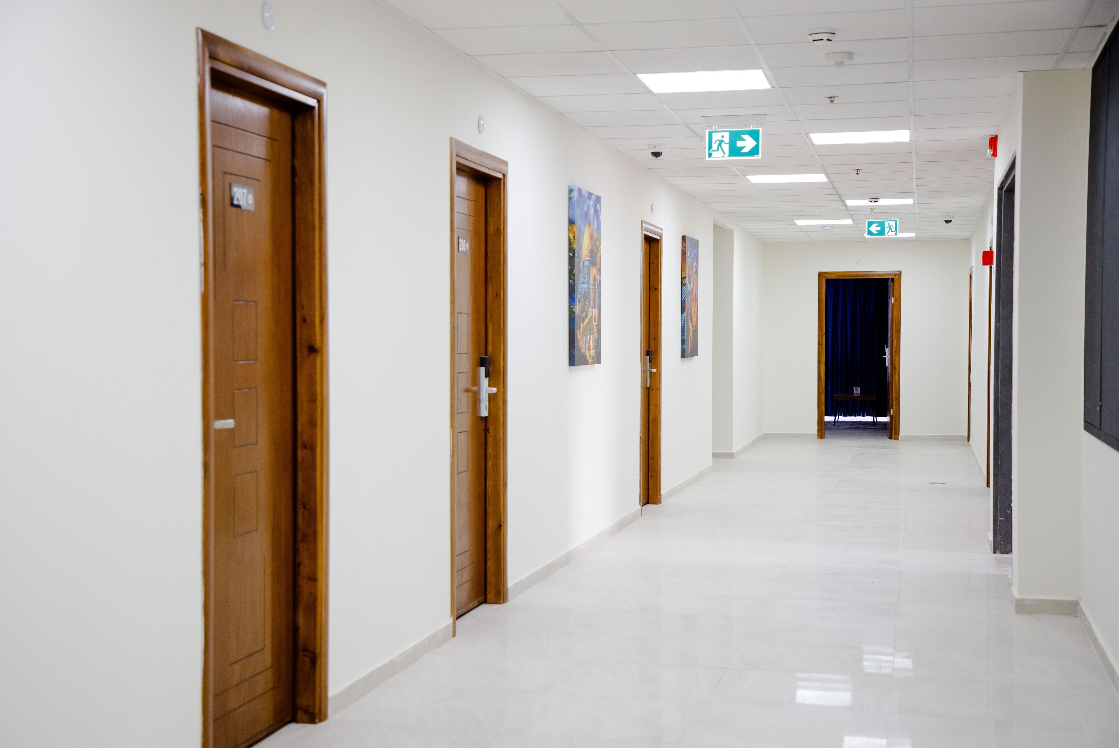 A long, narrow hallway with wooden doors on one side and a blue curtain at the end.
