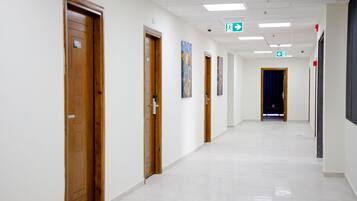 A long, narrow hallway with wooden doors on one side and a blue curtain at the end.