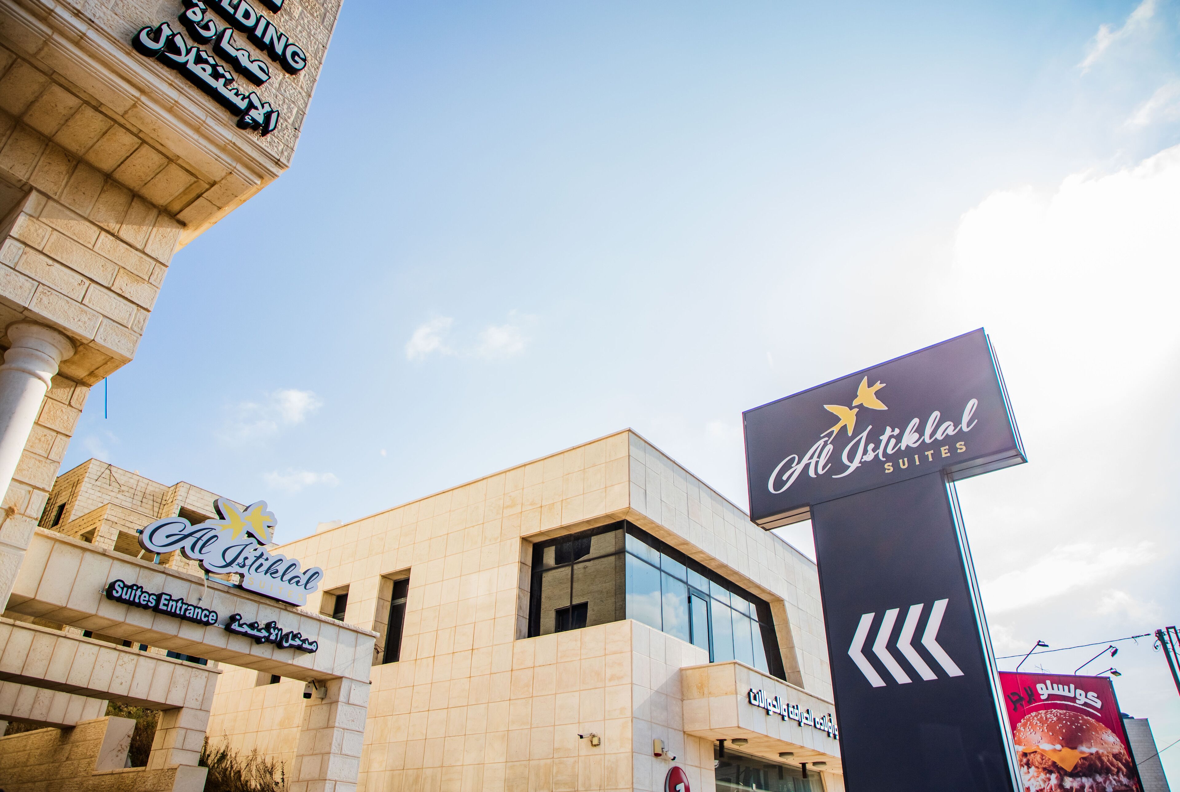 A hotel entrance with signage for Al Istiklal Suites and a Suites Entrance.