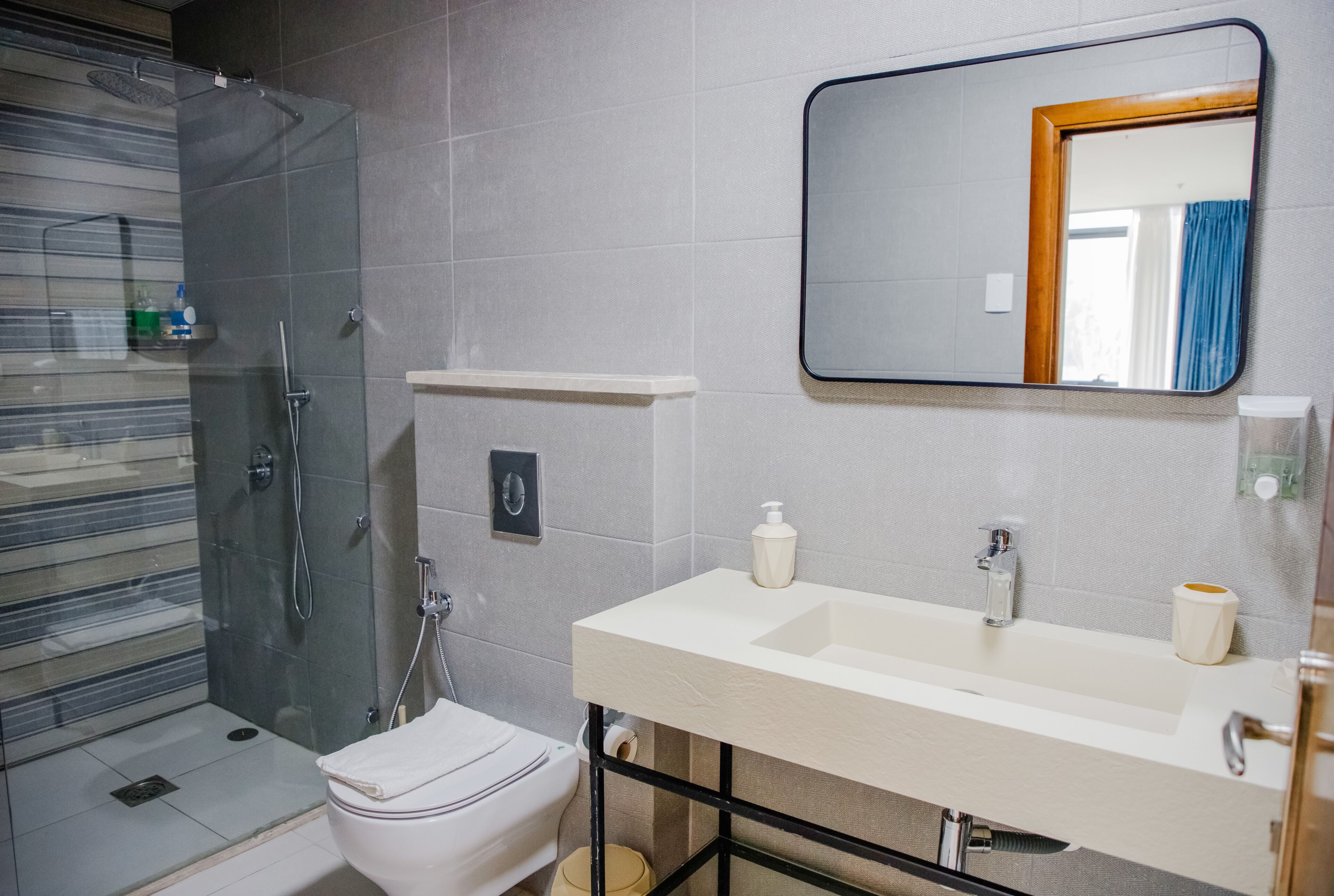 A modern bathroom with a glass shower enclosure, a white toilet, a sink with a mirror, and a towel rack.
