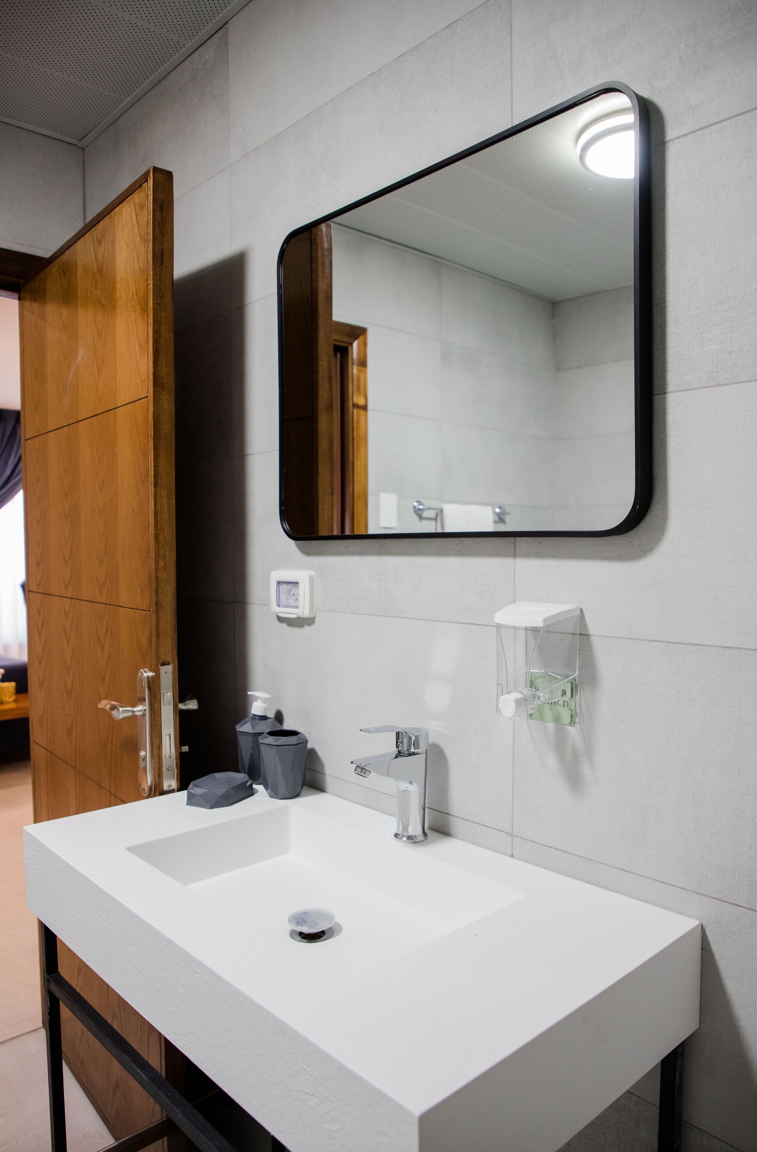 A bathroom with a white sink, a mirror, and a wooden door.