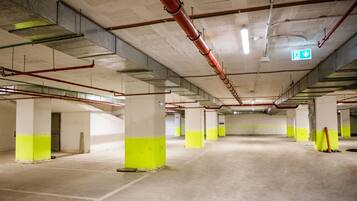 A multi-level parking garage with concrete pillars and overhead pipes.