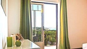 A room with a balcony, a table with a green candle, and a leopard print pillow. - Cozy Apartment w/ Pool in Albufeira (Albufeira)