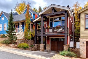 A two-story house with a stone foundation, a front porch with a staircase, and a garage.