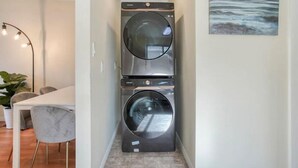 A compact laundry room with a washing machine and dryer stacked vertically. - Fort Charm (Fort Saskatchewan)