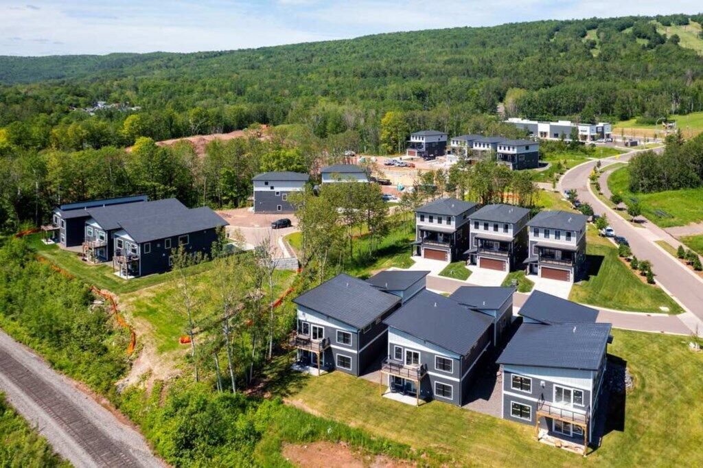 A residential area with modern houses, a road, and a railway track.