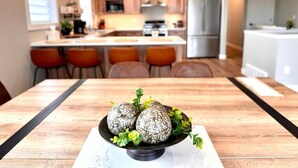 Een moderne keuken met houten kastjes, een centraal eiland met zitplaatsen en een eettafel met decoratief middelpunt.