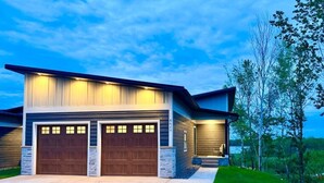Een modern herenhuis met garage, overdekte veranda en een verzorgd gazon.