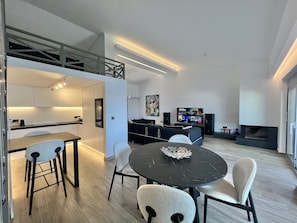 A modern living space with a kitchen, dining area, and entertainment setup.