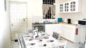 Una cocina compacta con armarios blancos, estufa, microondas y pileta.
