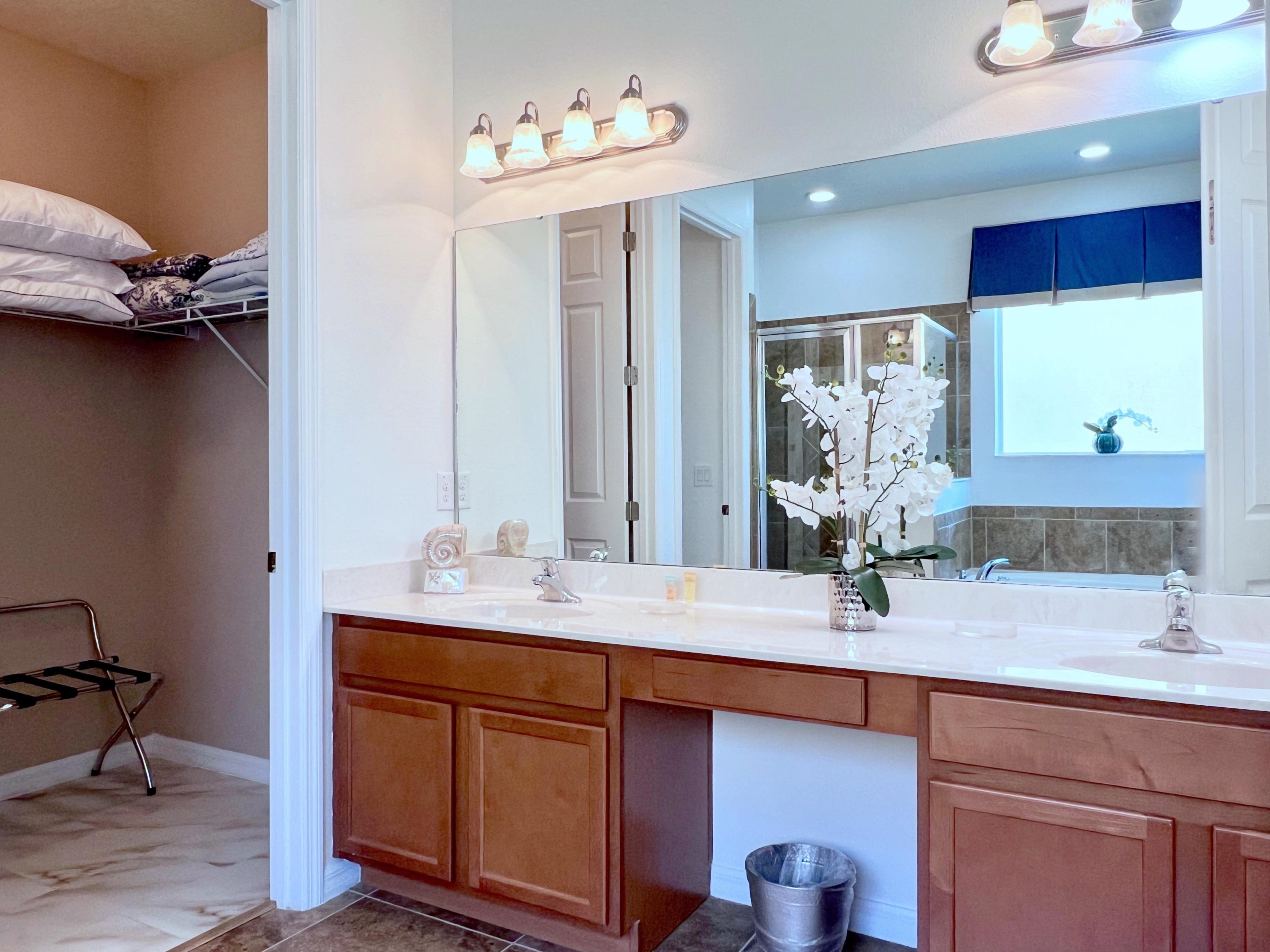 A bathroom with a double vanity, a large mirror, and a shower area visible through the glass door.