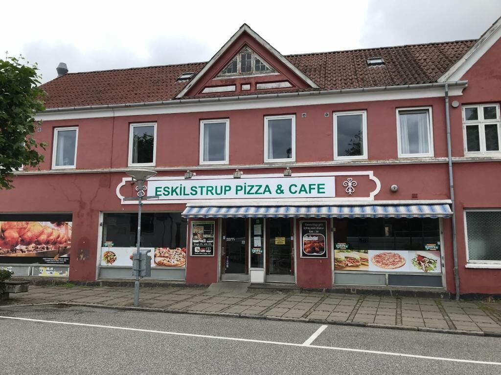 Un edificio de dos pisos con un letrero que dice "Eskilstrup Pizza & Cafe".