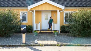 Una casa amarilla con una puerta blanca y un pequeño porche.