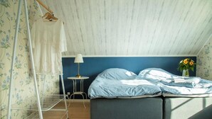 Un dormitorio con cama, mesita de noche, lámpara y ventana con cortinas.
