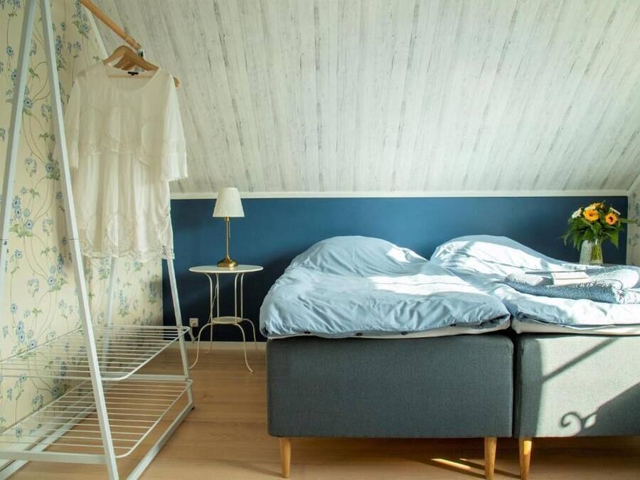 A bedroom with a bed, a nightstand, a lamp, and a window with curtains.