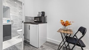 A compact kitchen with a microwave, a small refrigerator, and a wooden table with a chair. - Luxury Ensuite Room in Finsbury Pak London N19 (London)