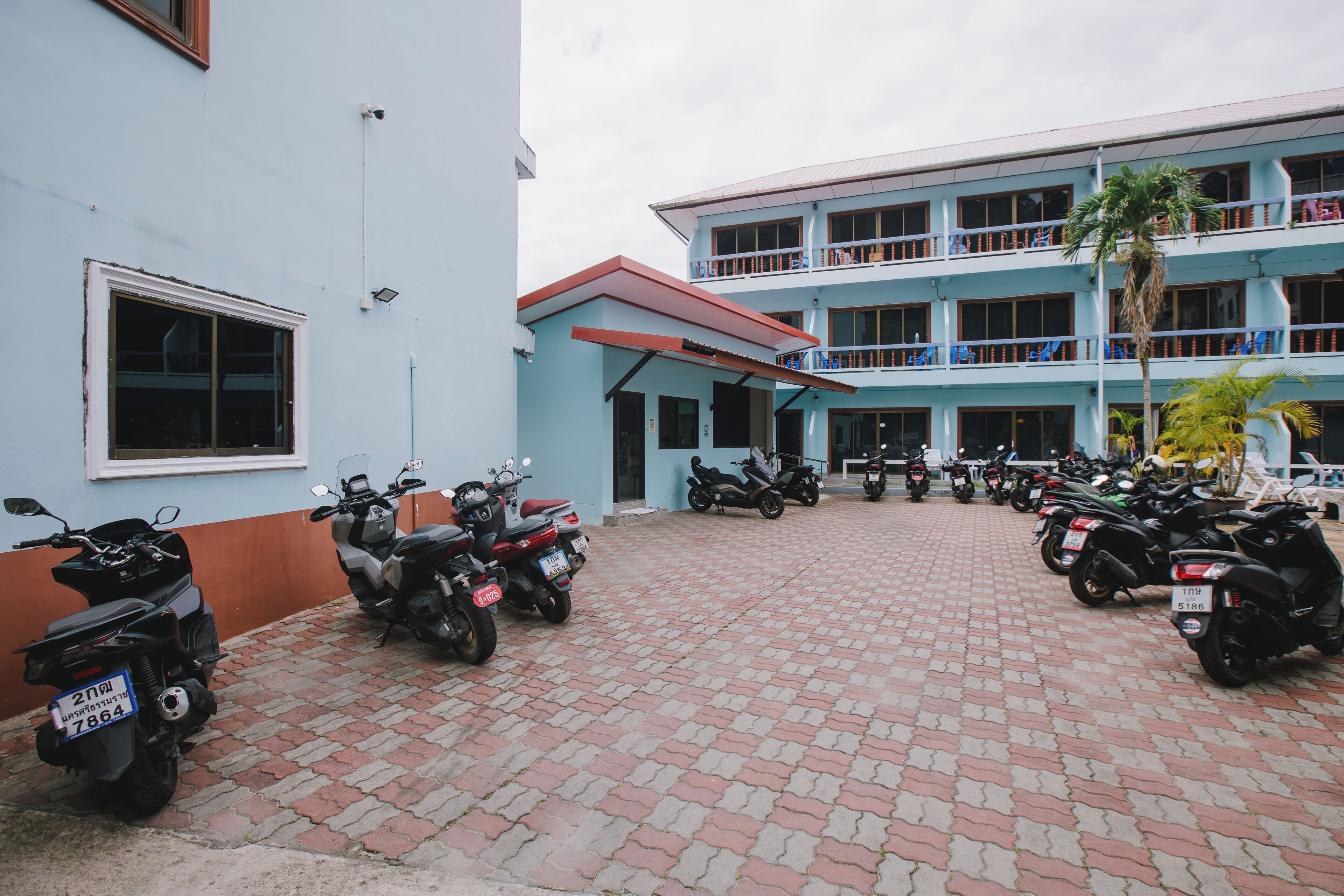 A building with a blue exterior and a red roof. There are several motorcycles parked in front of the building.