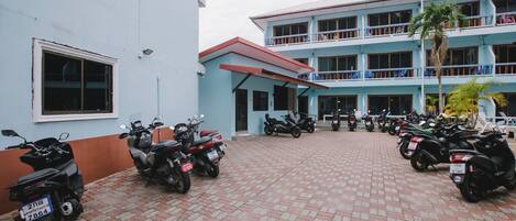 A building with a blue exterior and a red roof. There are several motorcycles parked in front of the building.