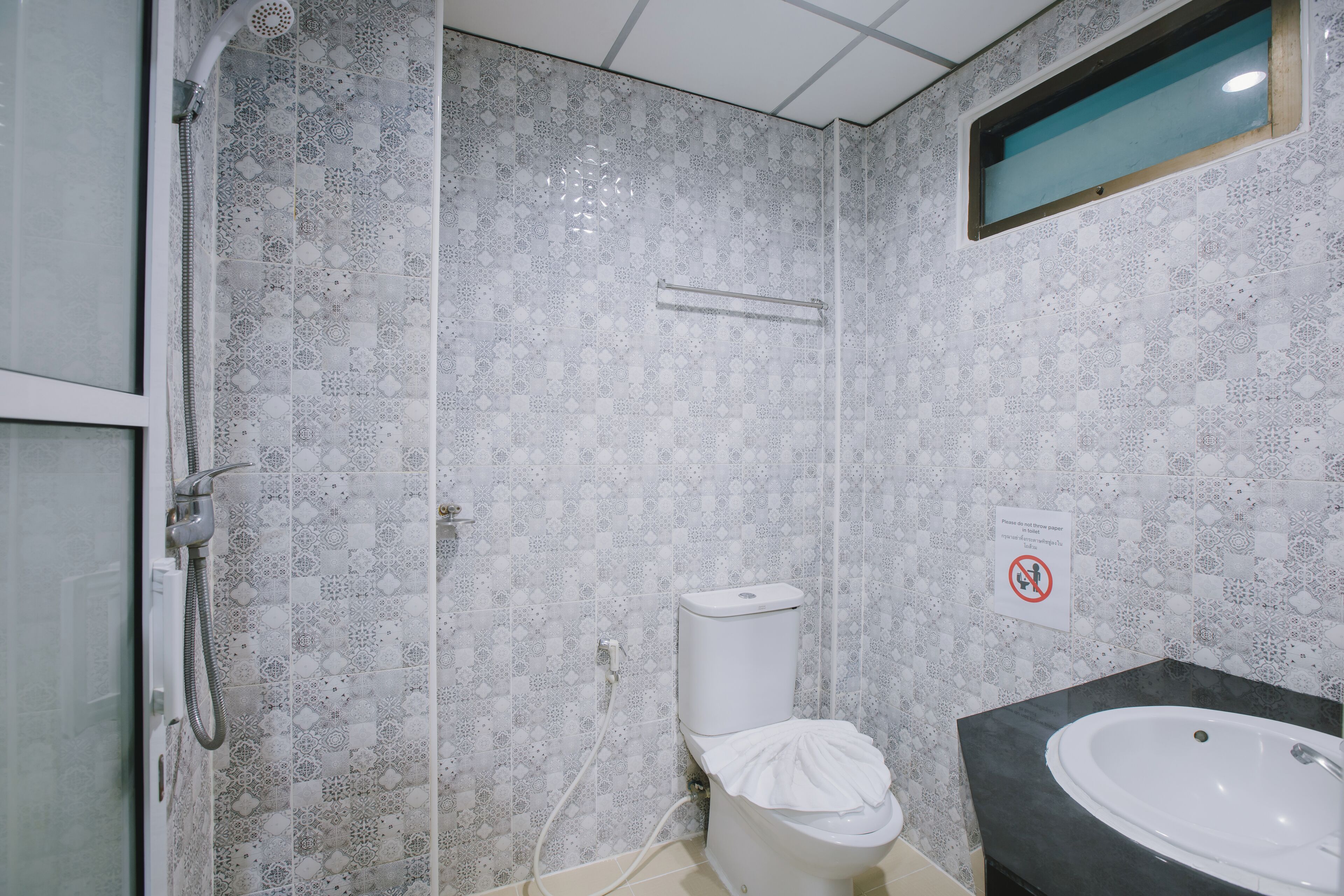 Un bagno con piastrelle decorative, un WC, una doccia e un lavandino.
