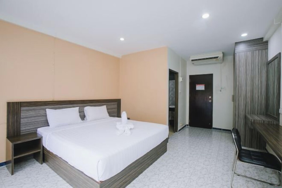 A hotel room with a bed, nightstand, wardrobe, and an air conditioning unit.