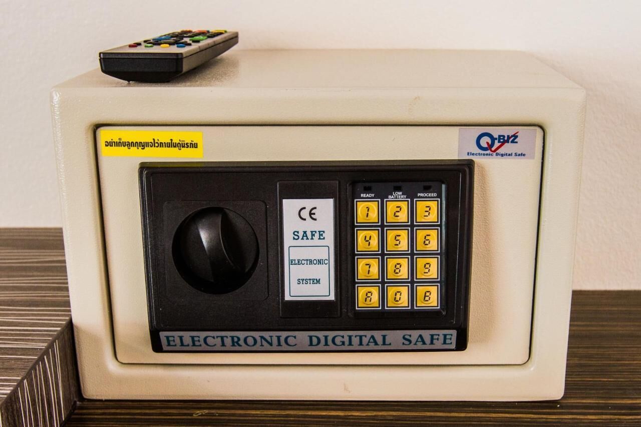 Un coffre-fort électronique numérique de couleur beige, doté d’un clavier et d’une télécommande situés sur le dessus.