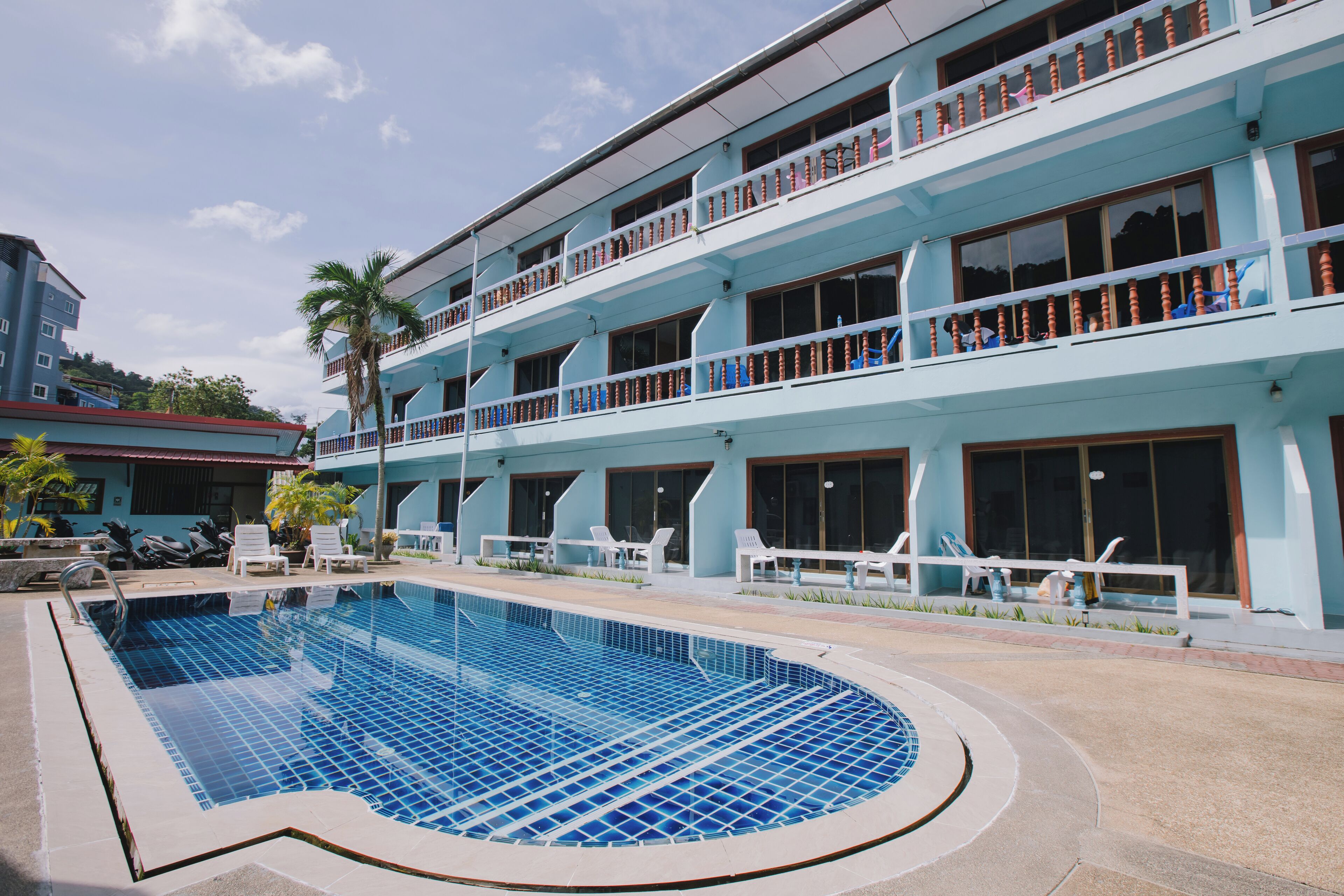 Ett hotell med en swimmingpool, flera balkonger och utomhusområden med sittplatser.