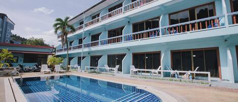 A hotel with a swimming pool, multiple balconies, and outdoor seating areas.