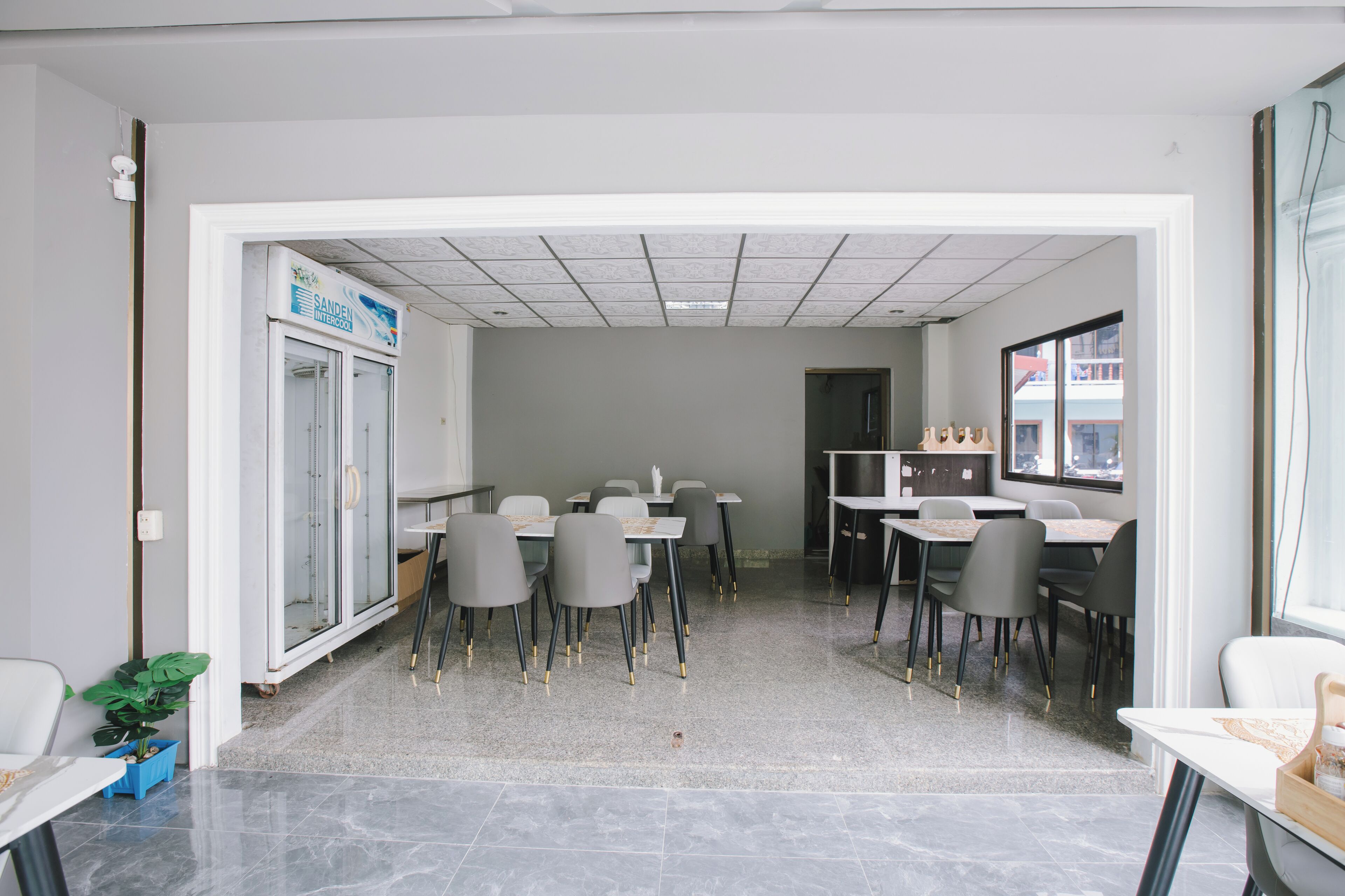 A modern office space with a meeting room, a kitchenette, and a dining area with tables and chairs.