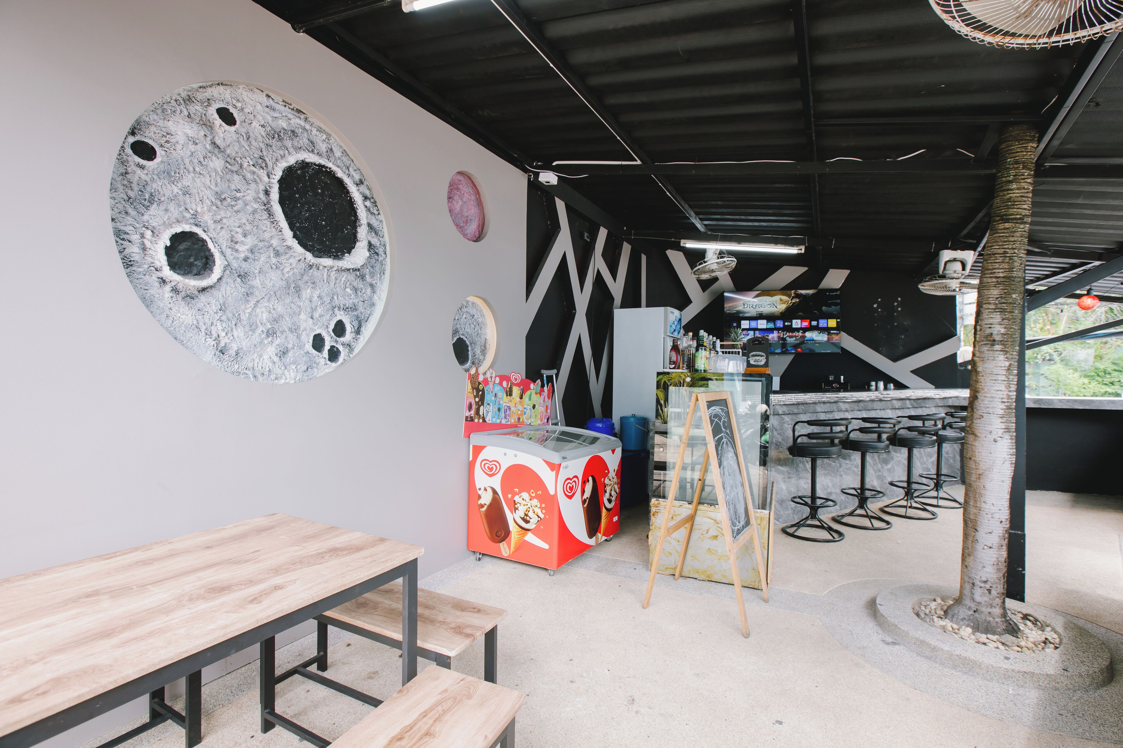 A bar area with stools, a counter, and a mural on the wall.