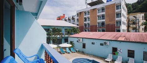 A pool area with lounge chairs and a view of surrounding buildings.