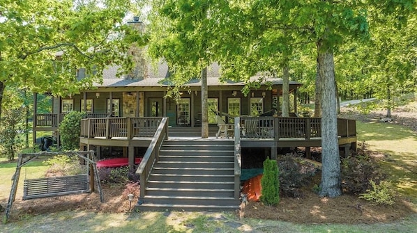 A two-story wooden cabin with a covered porch and a staircase leading to a deck.
