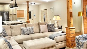 A modern living room with a sectional sofa, ottoman, and a dining area with a table and chairs. - Lake Martin, AL
43 min to Auburn University & Jordan-Hare Stadium (Dadeville)