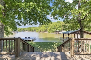 A lakeside deck with a view of a lake, surrounded by trees and a gazebo.