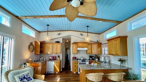 A spacious kitchen with wooden cabinets, a central island, and a ceiling fan.