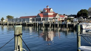 A waterfront building with a red roof, docked boats, and a clear blue sky.