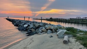 A rocky shoreline with a pier extending into calm waters.
