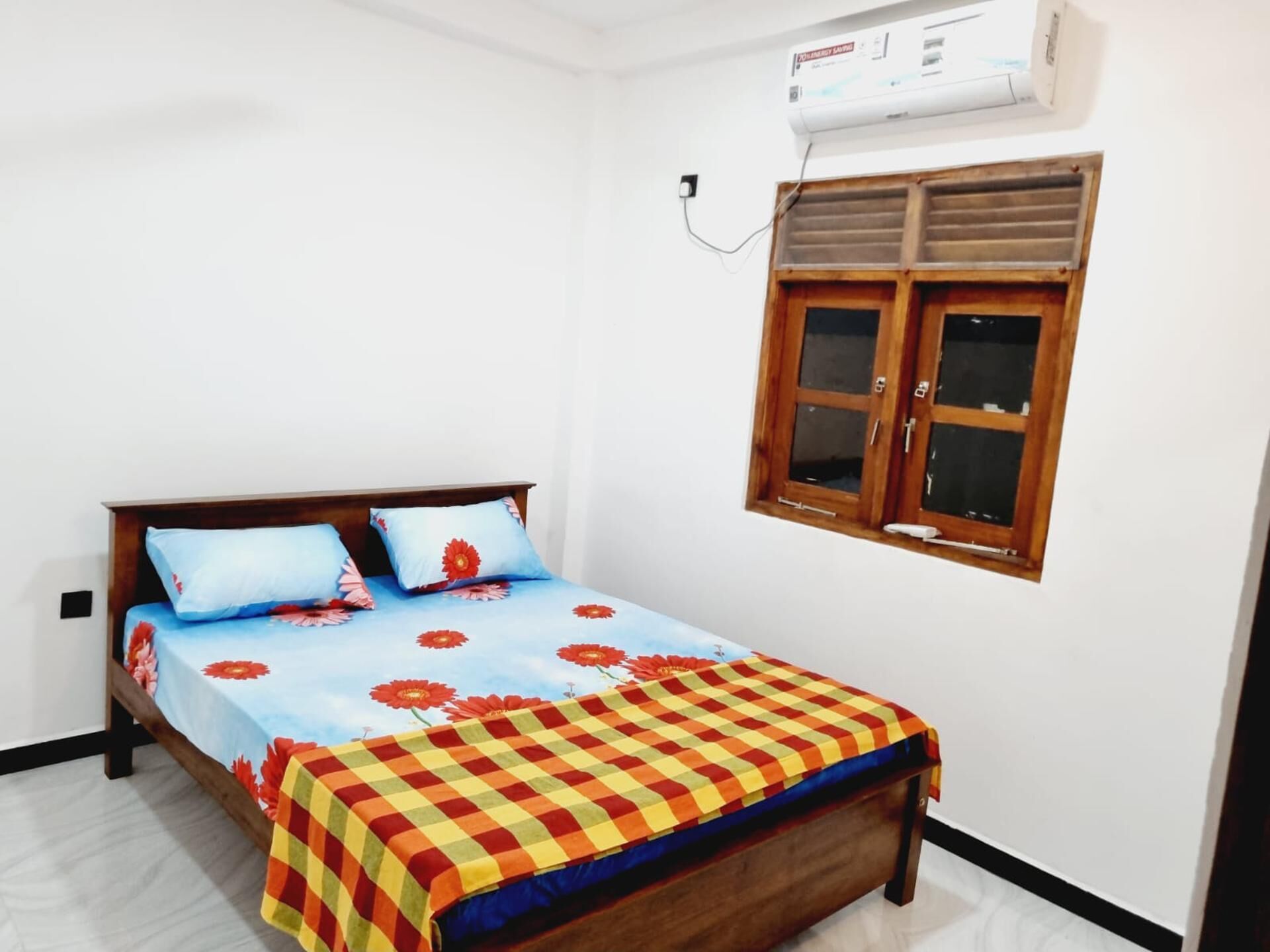 Un dormitorio con cama, ventana y aire acondicionado.
