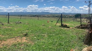 A rural landscape with a fenced field, scattered rocks, and distant mountains under a clear sky. - Hostal Valdeverdeja (Valdeverdeja)