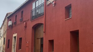 A red building with a balcony, a wooden door, and a window. - Hostal Valdeverdeja (Valdeverdeja)