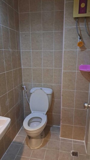 A small bathroom with a toilet, a shower area, and a sink. - Om Inn (Bangkok)