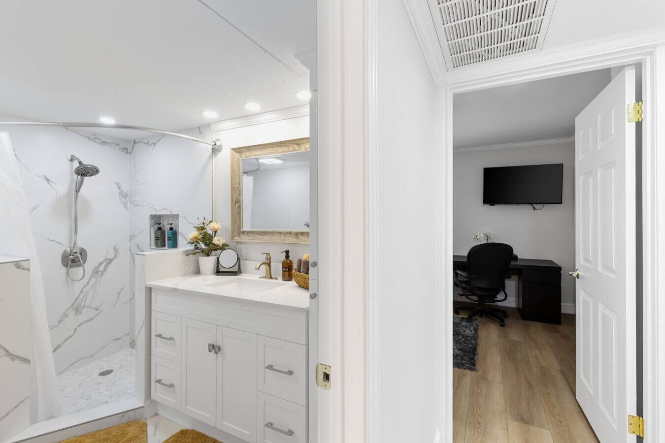 A modern bathroom with a shower, vanity, and a mirror.