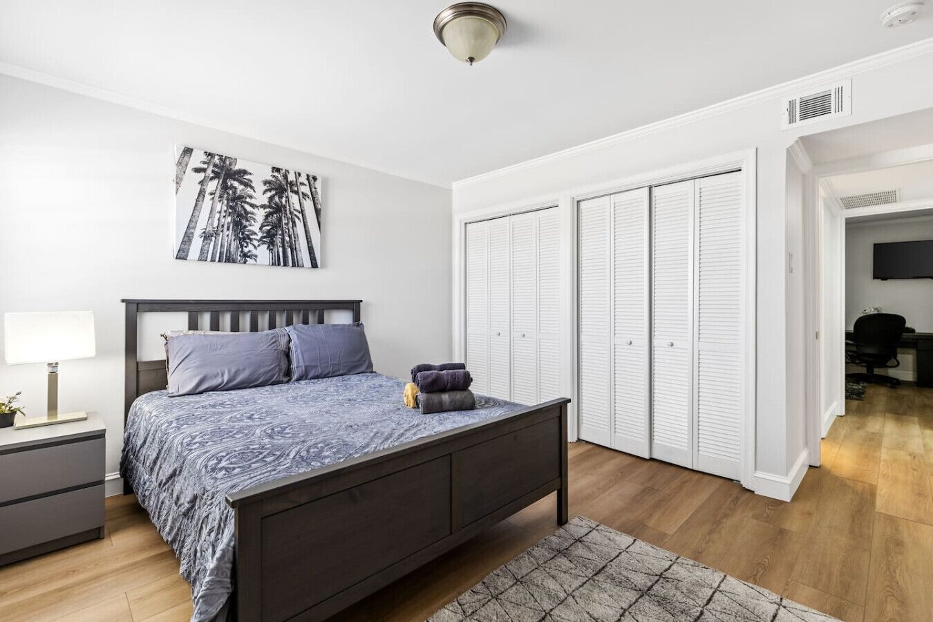 A bedroom with a bed, bedside table, lamp, and a large closet with sliding doors.