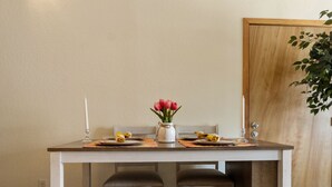 Une table à manger avec deux chaises, un vase de fleurs et une bougie.