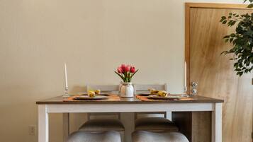 A dining table with two chairs, a vase with flowers, and a candle.
