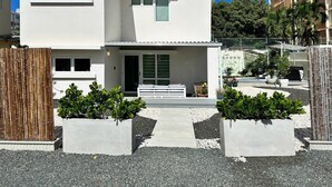 A modern two-story house with a white exterior, a front porch, and a gravel driveway.