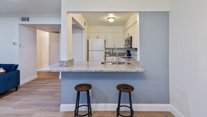 Una cocina moderna con encimera de granito, electrodomésticos de acero inoxidable y dos taburetes de bar.