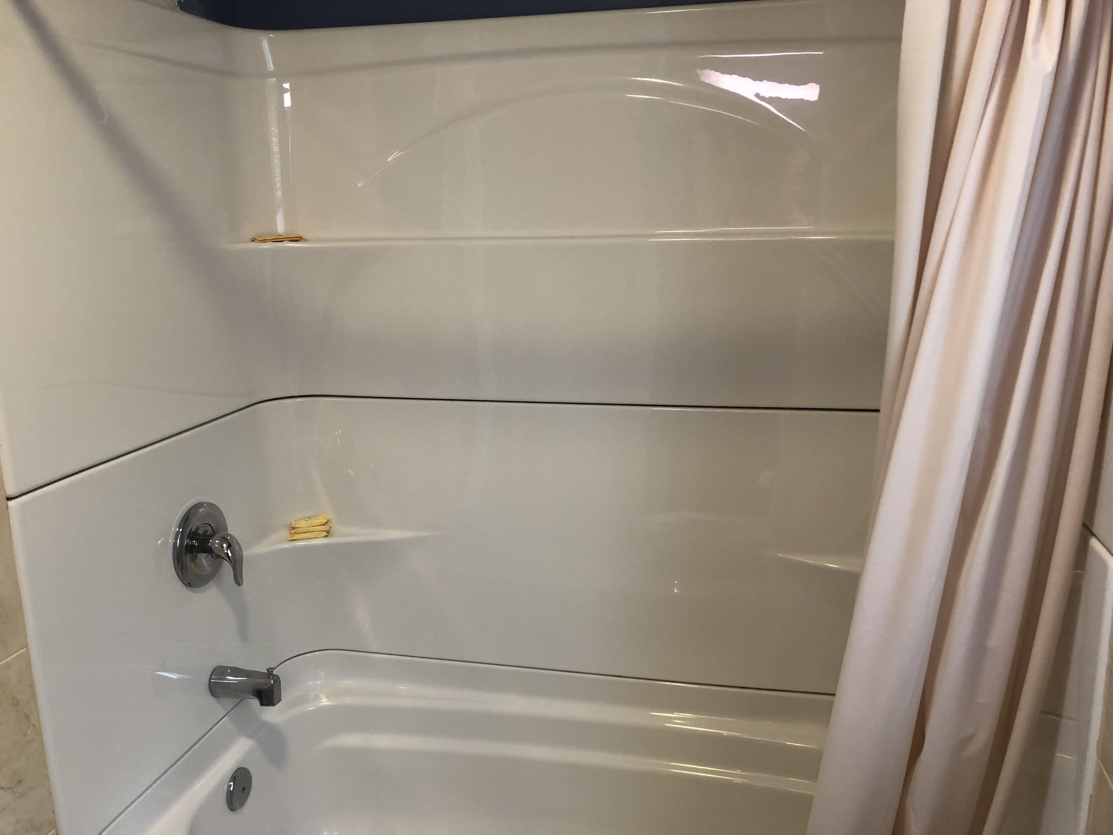 A bathroom with a bathtub, a shower curtain, and a towel rack.