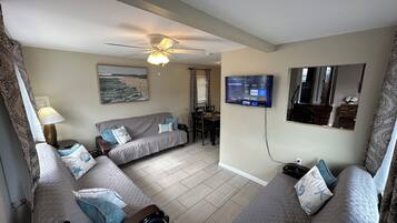 Relax in a stylish living area with a sofa, flat-screen TV, and coastal artwork.