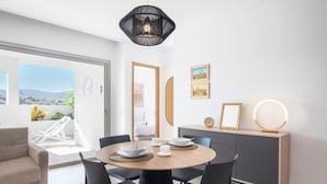 A dining area with a round table, black chairs, a sofa, a cabinet with decorative items, and a view of the outdoors. - Jardines - Acoran 2.5 RESERVE NATURE VIEW 1B (Arona)